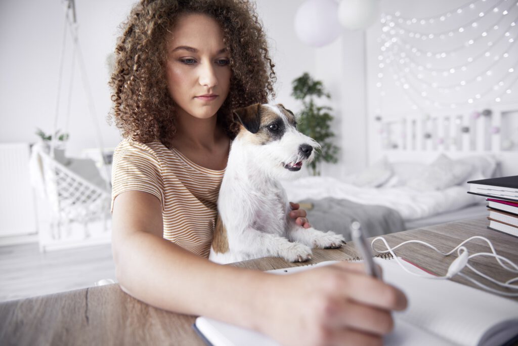 Teenage girl and her dog studying together