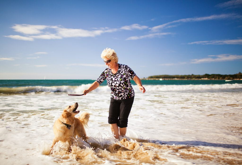 Woman playing on the beach with golden retriever
